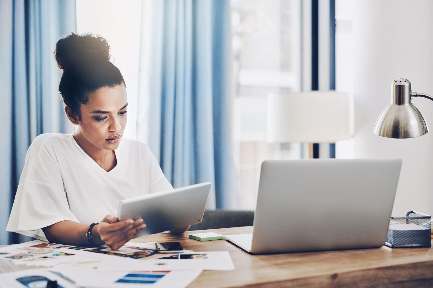 Woman working at a desk with a tablet and computer